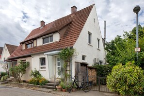 A two-story house with a sloped roof, a front door, and a bicycle parked outside.