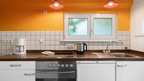 Een kleine keuken met een vaatwasser, oven en koffiezetapparaat op het aanrecht.