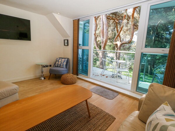 Una sala de estar moderna con un ventanal grande, un sofá, una mesa de centro y una butaca.