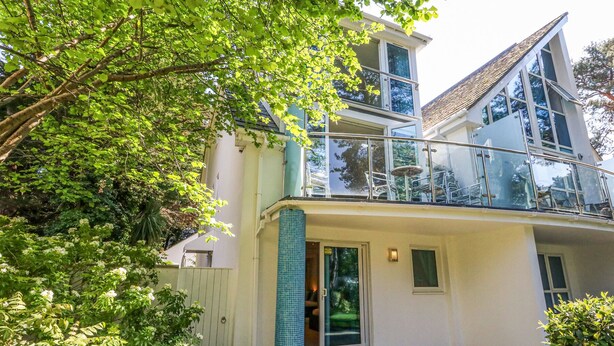 Een modern huis met twee verdiepingen, een balkon, een glazen deur en een betegelde zuil.