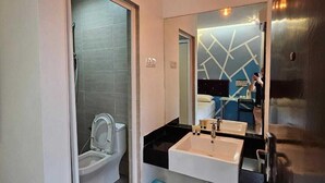 A modern bathroom with a glass shower enclosure, a white toilet, a double sink vanity, and a mirror reflecting the room. - V Garden Hotel by Minsu (Kuala Lumpur)