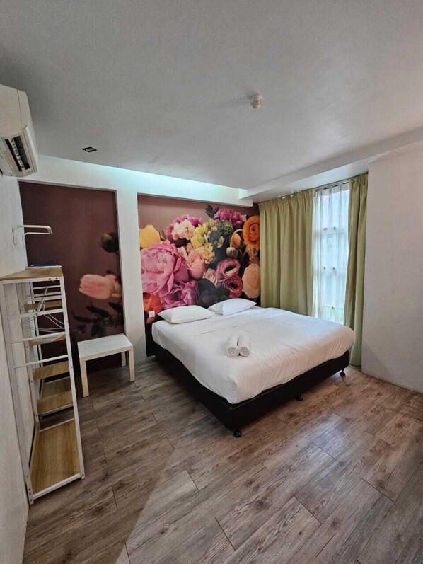 A bedroom with a bed, a small bedside table, a wall-mounted shelf, and a window with curtains. - V Garden Hotel by Minsu (Kuala Lumpur)
