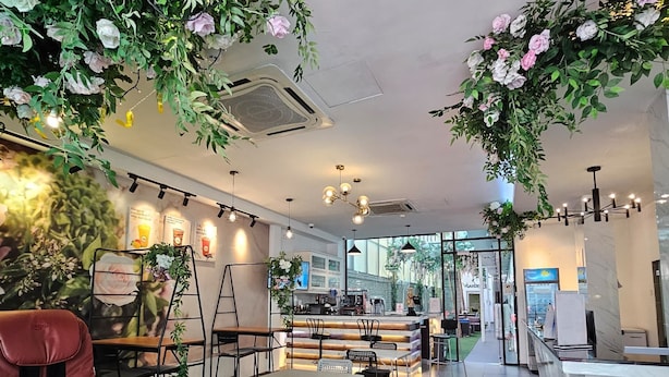 A modern cafe with a central counter, seating area, and decorative plants. - V Garden Hotel by Minsu (Kuala Lumpur)