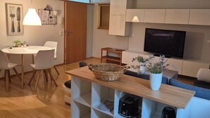 Une cuisine moderne avec un coin repas, des placards intégrés, un téléviseur et une table à manger en bois.
