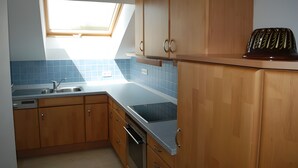 Eine Küche mit Holzausstattung, einem Einbauofen, einem Geschirrspüler und einem Oberlicht.