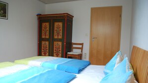 Ein Schlafzimmer mit zwei Betten, einem Holzschrank, einer Holztür und einem Stuhl.