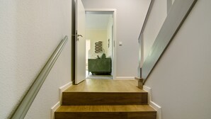 Una escala que condueix a una habitació amb un sofà verd i una obra d'art penjada a la paret.