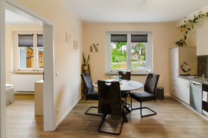 Een moderne keuken met een eethoek, witte kasten en uitzicht op het omliggende landschap.