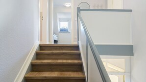A staircase with wooden steps and a metal handrail, leading to a room with a window and a door. - Apartment 'Wohnung 3' with Shared Terrace, Shared Garden and Wi-Fi (Bad Karlshafen)