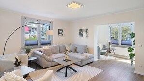 A modern living room with a sofa, coffee table, and a view of the outside. - Apartment 'Wohnung 3' with Shared Terrace, Shared Garden and Wi-Fi (Bad Karlshafen)