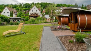 A modern building with a unique cylindrical design, a grassy area with a lounge chair, and a paved walkway. - Apartment 'Wohnung 3' with Shared Terrace, Shared Garden and Wi-Fi (Bad Karlshafen)