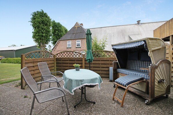 A patio area with a table, two chairs, and a sofa.