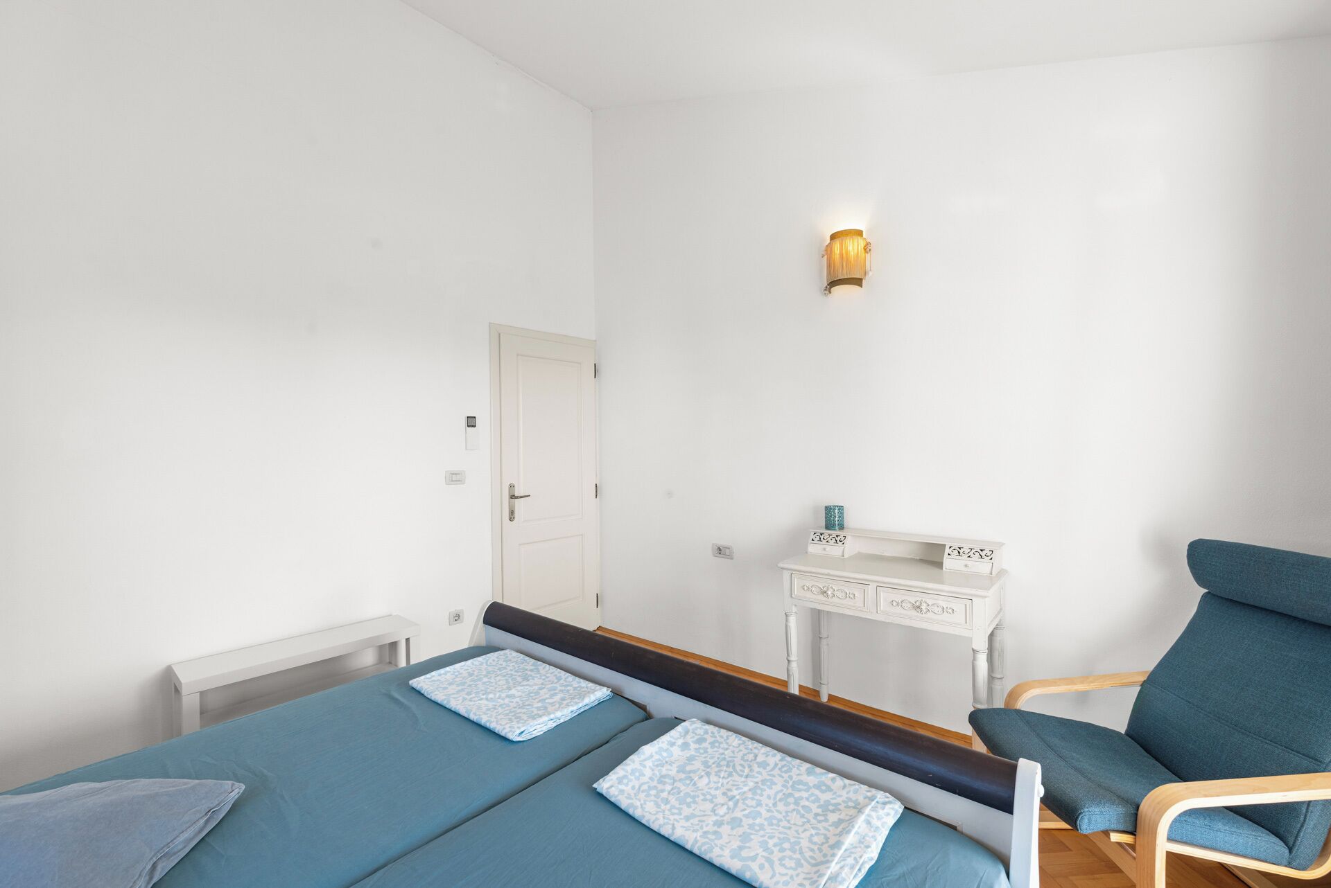 Ein Schlafzimmer mit Bett, Nachttisch, Stuhl und Wandlampe.