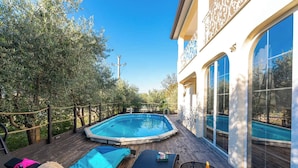 A pool area with lounge chairs and a small table, surrounded by a wooden deck and a fence. - Holiday House with Pool Villa Seabird (Porec)
