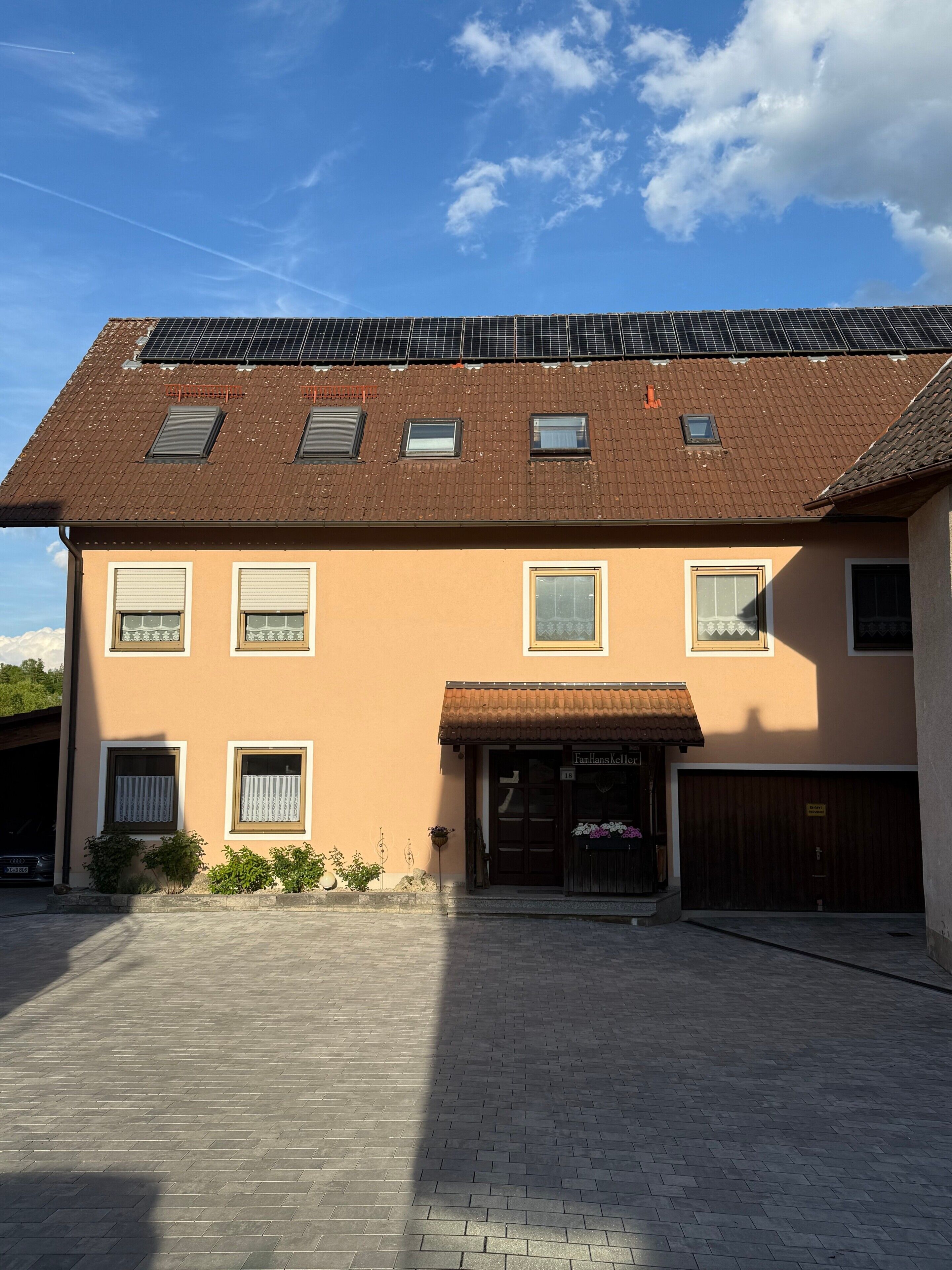 A two-story building with a brown roof, multiple windows, and a paved driveway.