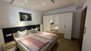 Une chambre à coucher avec un lit, des tables de chevet, une armoire et un miroir.