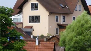 Un immeuble résidentiel à plusieurs étages, doté d’un toit en pente, de nombreuses fenêtres et d’une cheminée bien visible.