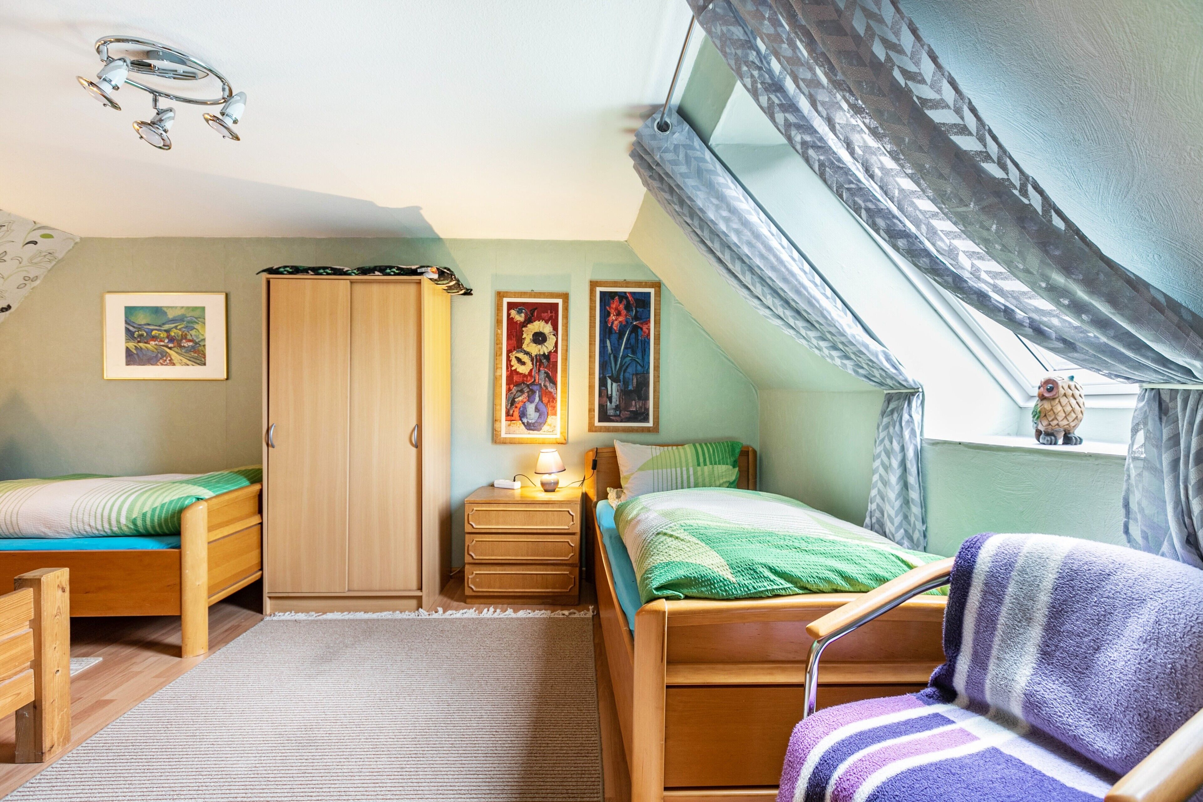 Une chambre à coucher avec deux lits en bois, une table de chevet, une armoire et une fenêtre donnant sur un beau paysage.