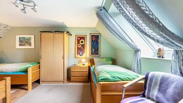 Une chambre à coucher avec deux lits en bois, une table de chevet, une armoire et une fenêtre donnant sur un beau paysage.