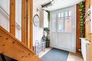 A wooden staircase leading to a white door with a mirror, a radiator, and a plant. - Holiday Home 'Altstadt Ferienhaus Mit Terrasse' with Private Terrace and Wi-Fi (Husum)