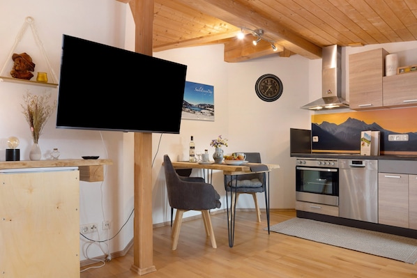 Eine moderne Küche mit Holzschränken, einem eingebauten Ofen und einem Essbereich mit Tisch und Stühlen.