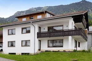 Ein zweistöckiges Gebäude mit Balkon, Fenstern und Bergblick.