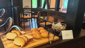 Une planche à découper en bois, sur laquelle on voit du pain tranché et des petits pains ronds, posée sur un comptoir.