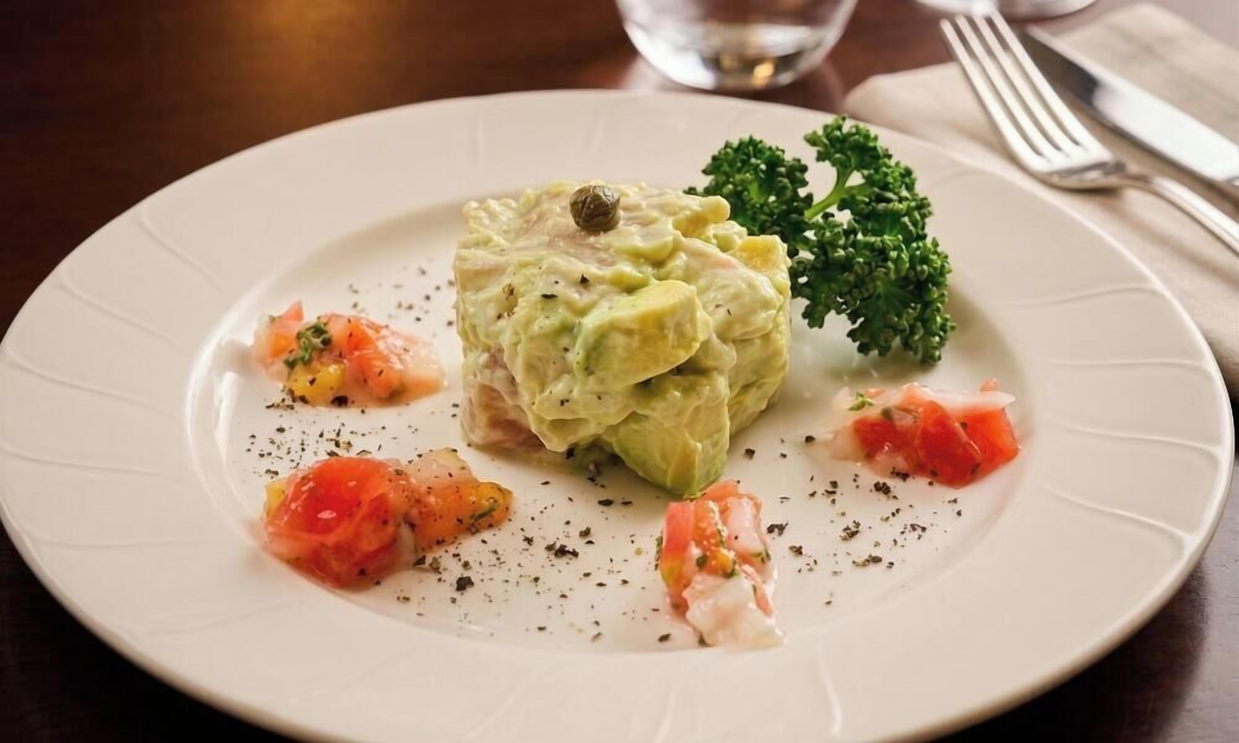 Un plato con ensalada verde, un trozo de carne y una guarnición sobre un plato blanco.