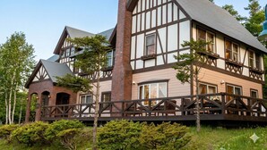 Un grand immeuble à plusieurs étages, doté d’une cheminée imposante, de nombreuses fenêtres et d’un balcon avec des balustrades en bois.