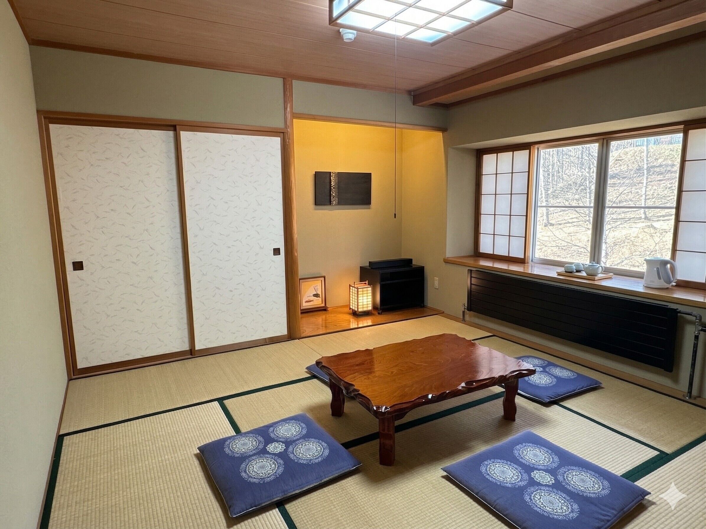 Una habitación japonesa tradicional con suelo de tatami, una mesa de madera baja y puertas correderas shoji.