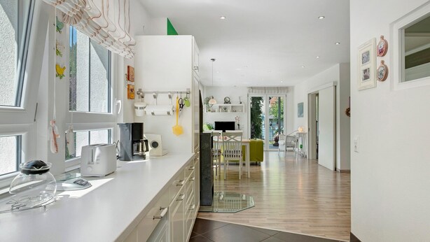 A modern kitchen with a white countertop, a toaster, and a glass container.