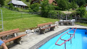 Una piscina con muelle de madera, bancos y un muro de piedra.
