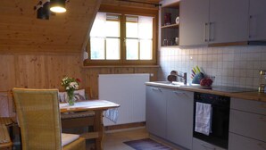 Una cocina acogedora con una mesa de comedor, sillas de mimbre, un radiador, un fregadero y una estufa.