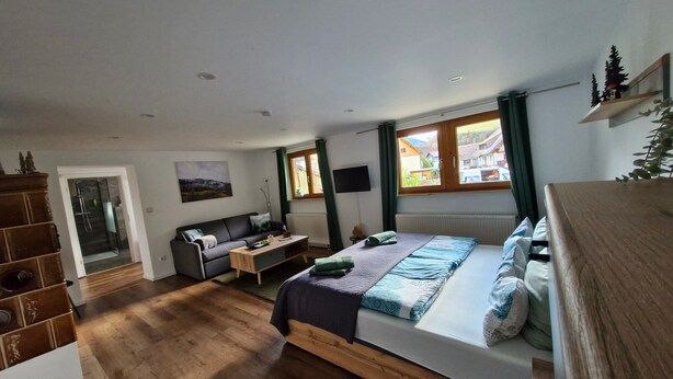 Une chambre avec un lit, un canapé, une télévision et une fenêtre donnant sur un beau paysage.