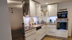 Une cuisine moderne dotée d’appareils électroménagers en acier inoxydable, de meubles blancs, d’un plan de travail en bois et d’un élément décoratif mural.