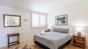 Una camera da letto con un letto, comodini, uno specchio e un quadro appeso al muro.