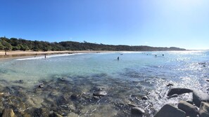 A beach with clear water, rocks, and people.