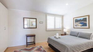 A bedroom with a bed, bedside table, lamp, and a painting on the wall.
