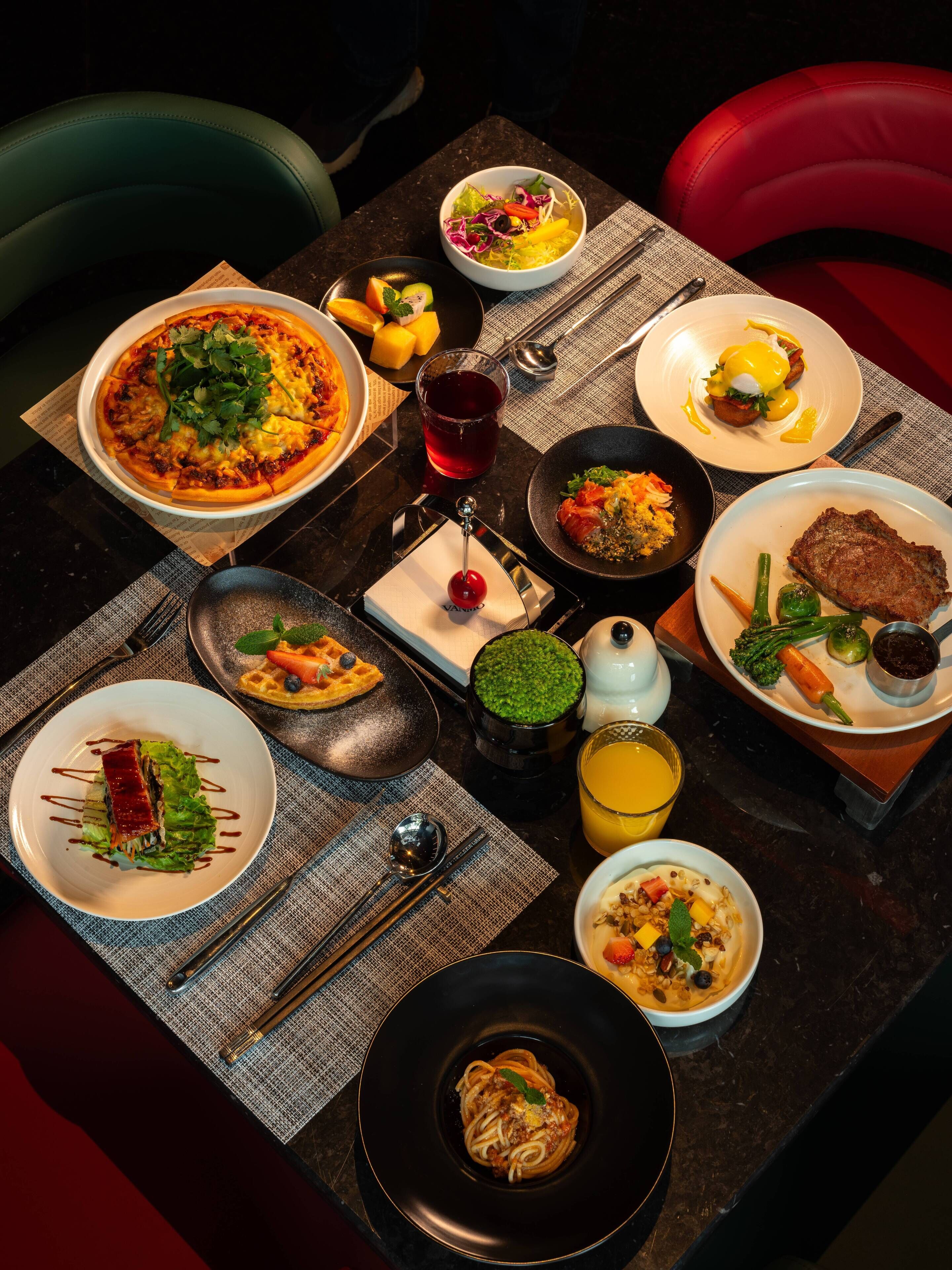 Una mesa de comedor con varios platos, como pasta, carne y una ensalada.