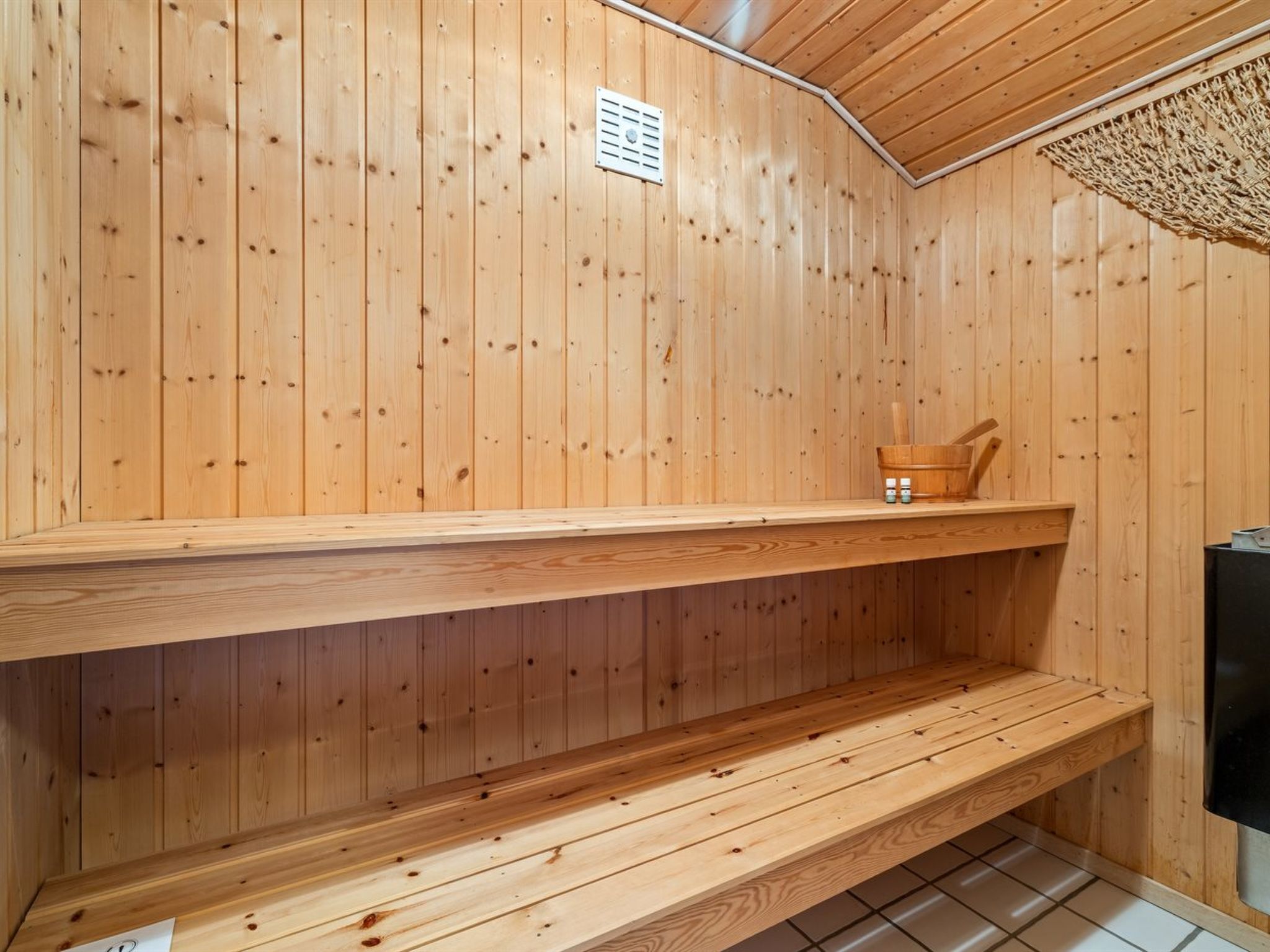Un sauna en bois avec deux bancs et un seau en bois.