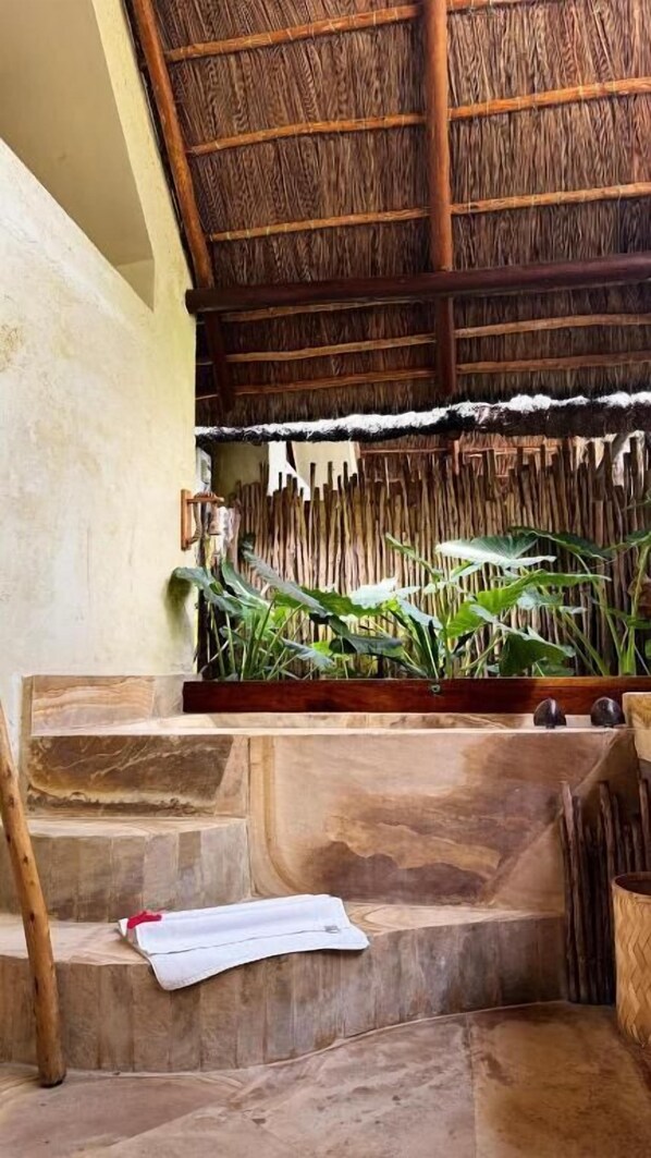 A room with a thatched roof, a wooden bench, and a staircase leading to an upper level. - The Nest Boutique Resort (Paje)