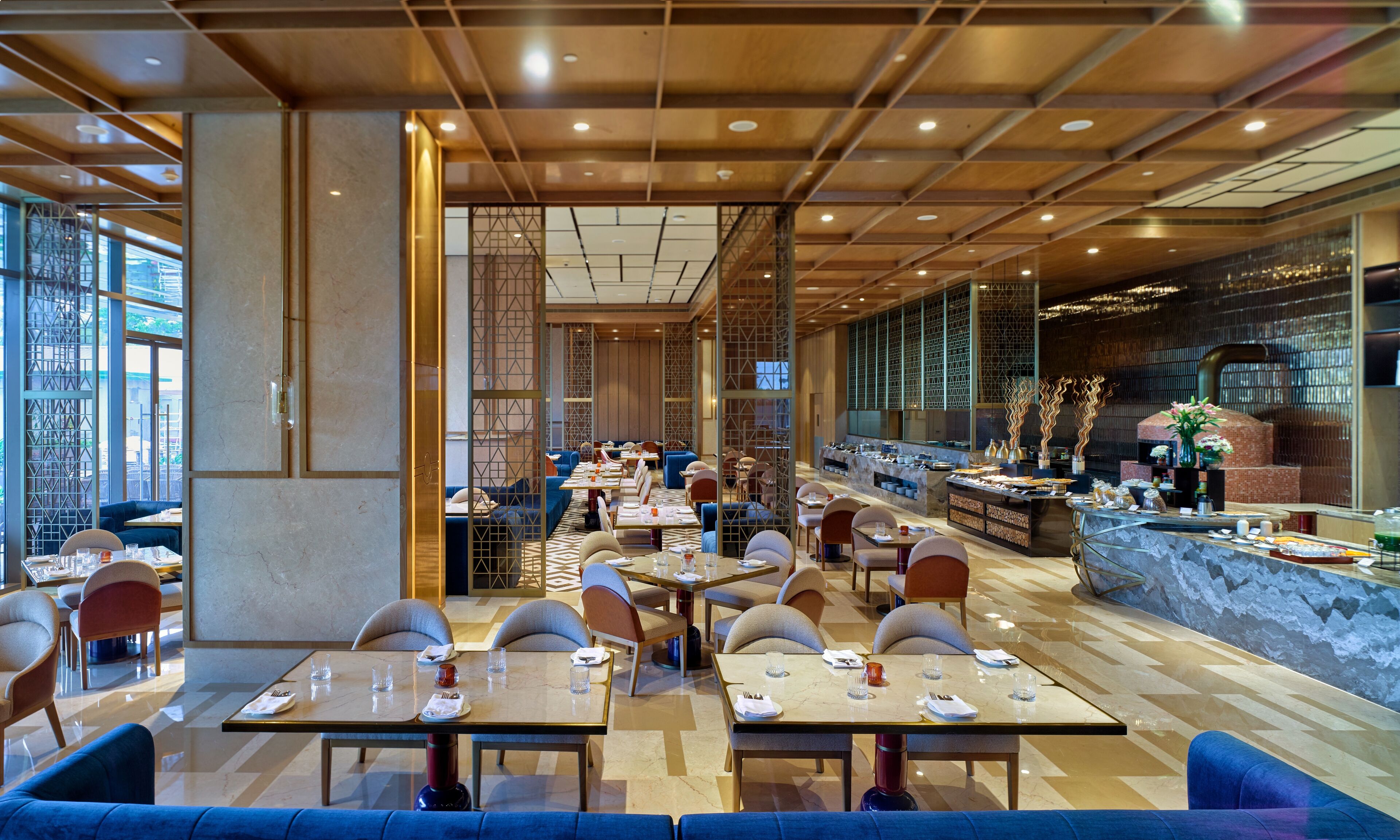 A modern restaurant with a long counter, multiple seating areas, and a decorative wall.