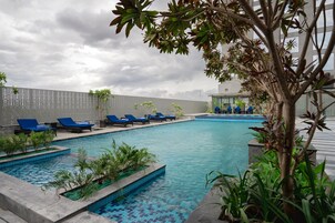 Una piscina con sillas reclinables azules y plantas en macetas.