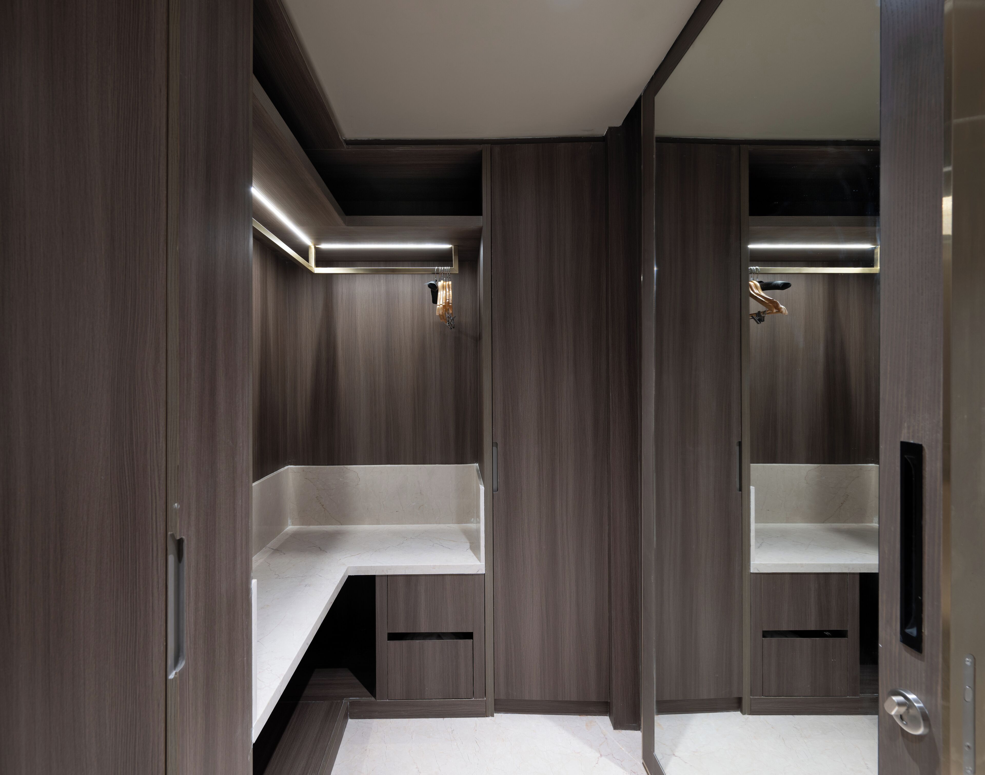 A modern bathroom with dark wood paneling, a white marble countertop, and a built-in shower area.