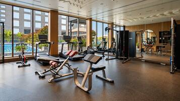 Ein modernes Fitnessstudio mit Cardiogeräten, Krafttrainingsgeräten und einem großen Spiegel.