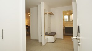 Une chambre d’hôtel moderne dotée d’une banquette intégrée, d’un miroir et d’un petit coin salon.