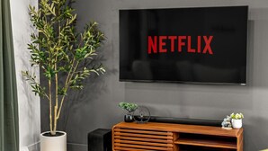A modern living room with a flat-screen TV mounted on the wall displaying the Netflix logo. - Modern Arvada Suite | Sauna & Games (Arvada)