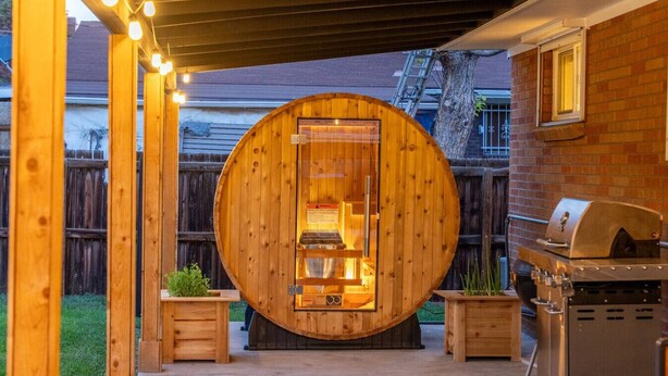A wooden outdoor kitchen with a circular wooden structure, a barbecue grill, and a wooden table with plants. - Modern Arvada Suite | Sauna & Games (Arvada)