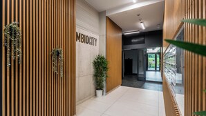 A modern interior with vertical wooden panels, a potted plant, and a sign reading "MBI CITY". - Luxurious Brand New! Private Jacuzzi + Terrace + Parking (Warszawa)