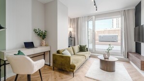 A modern living room with a sofa, a coffee table, a TV, and a desk with a laptop. - Luxurious Brand New! Private Jacuzzi + Terrace + Parking (Warszawa)